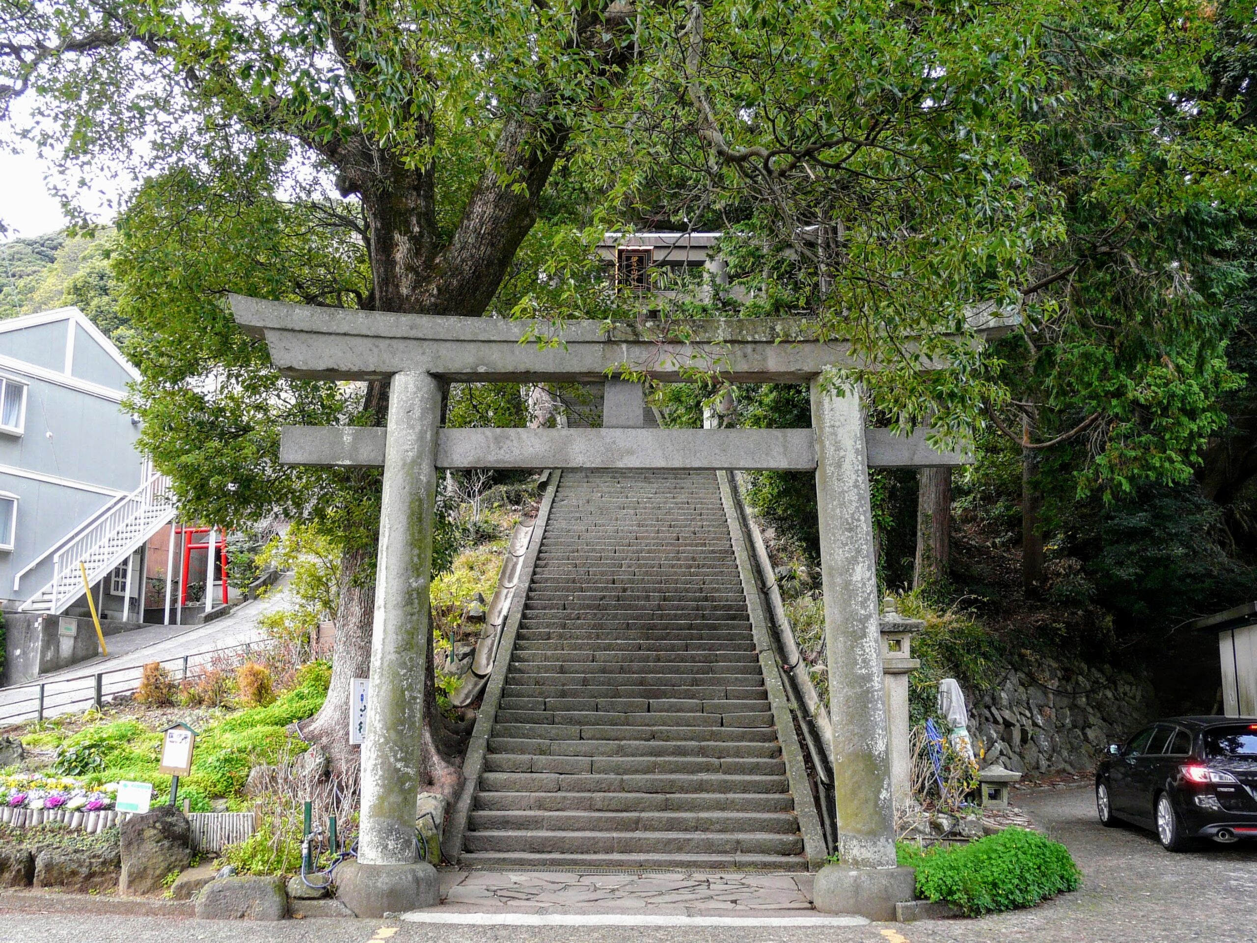 Stone torii gate and approach stairs of Izusan Shrine, surrounded by green trees