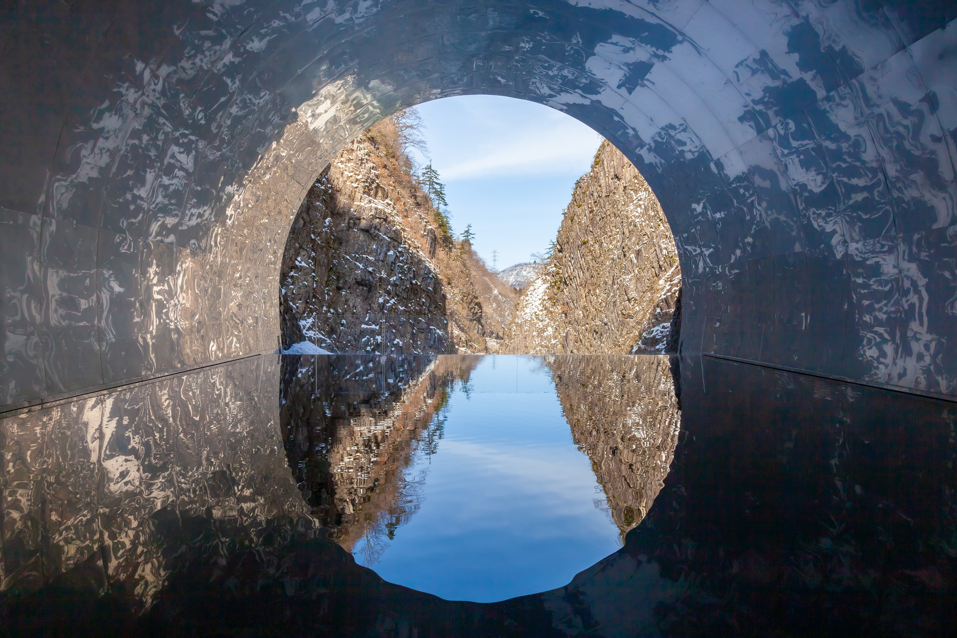 The Tunnel of Light at Kiyotsu Gorge: a mirror pool at the end of the tunnel reflecting the gorge's rock walls and sky
