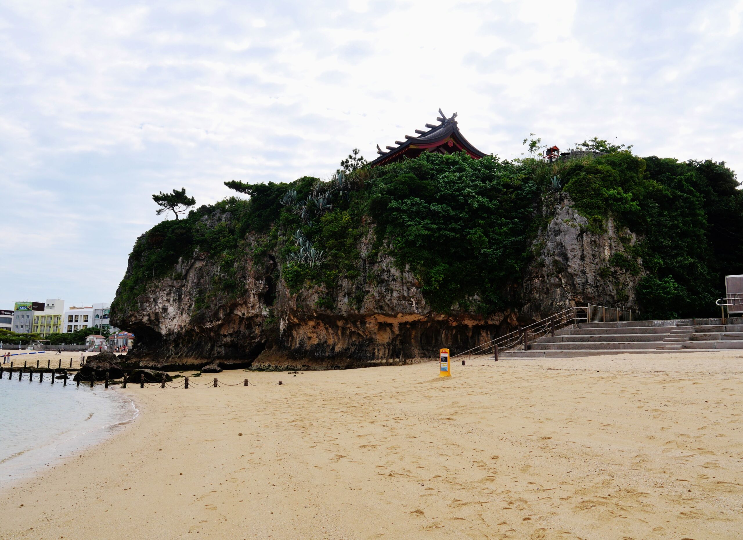 Naminoue Beach with the shrine cliff rising dramatically behind it