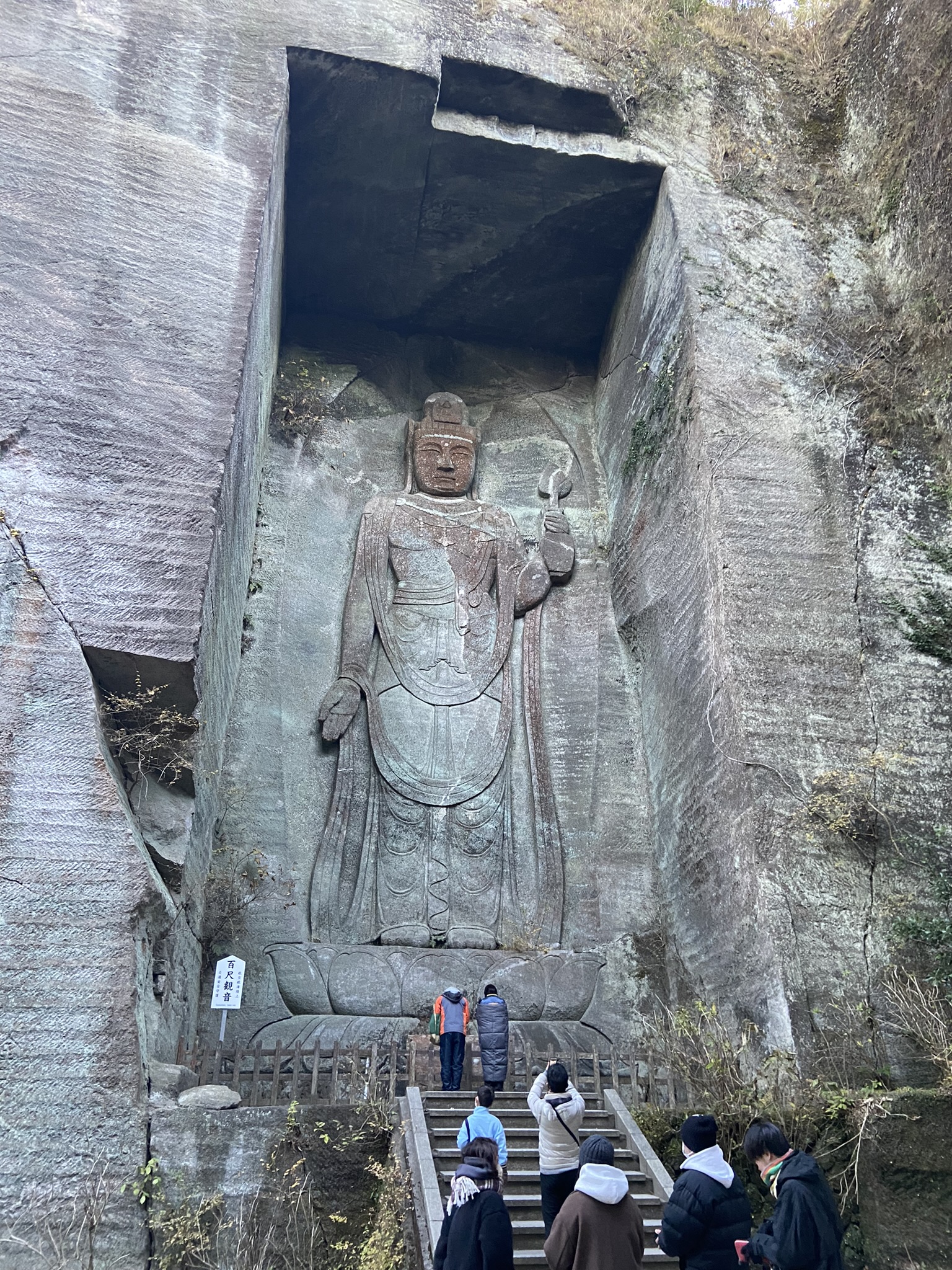 崖面に彫られた巨大な磨崖仏。階段を上る参拝者と比較するとその大きさがわかる