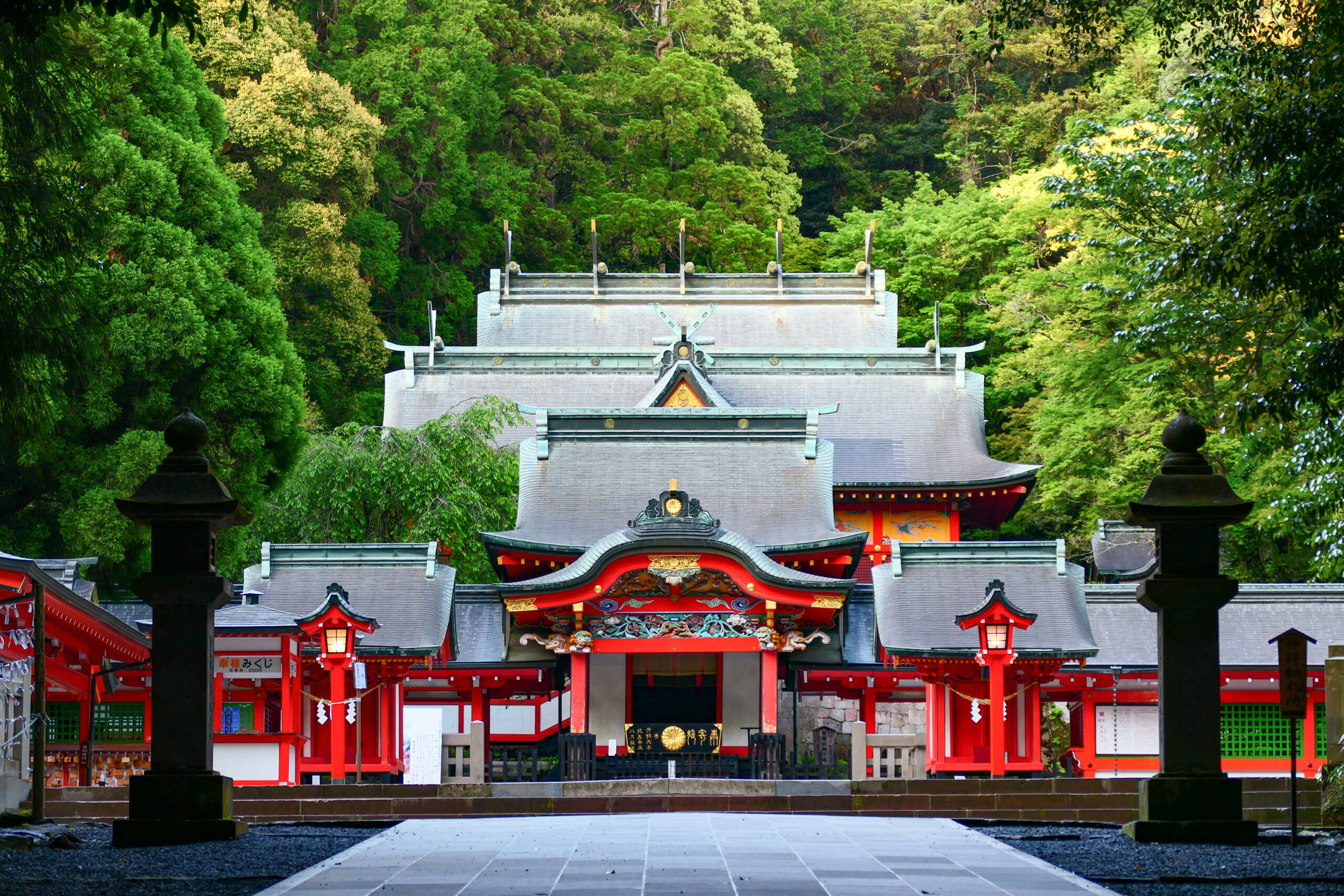 The main hall of Kirishima Jingu, vermilion buildings set against deep green forest